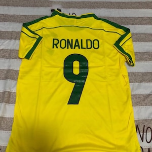 May include: A yellow football shirt with green detailing. The name "RONALDO" is printed on the back in black, with the number "9" below in green. The shirt is made of a lightweight fabric.