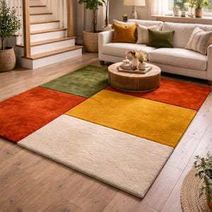 May include: A colorful area rug with a patchwork design. The rug features squares of orange, green, yellow, and cream colors, creating a vibrant and modern look. The rug is placed on a hardwood floor in a living room setting.