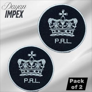 May include: Two circular black embroidered patches with a silver crown design and the letters "P.R.L." The patches are outlined in silver. The text "Dayan IMPEX" is in the upper left corner. The text "Pack of 2" is in the lower right corner.