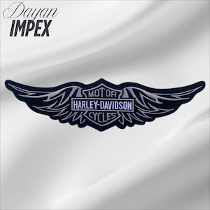 May include: A black and white Harley-Davidson Cycles embroidered patch with a wing design. The patch features the text "MOTOR HARLEY-DAVIDSON CYCLES" in a rectangular frame. The patch is set against a white background. The text "Dayan IMPEX" is in the upper left corner.