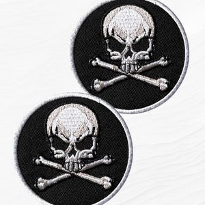 May include: Two embroidered patches featuring a skull and crossbones design. The skull is white, with a black background and a white border. The text "Dayan IMPEX" is in the upper left corner.
