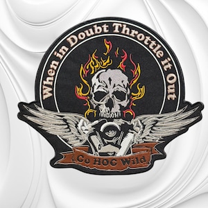May include: A circular embroidered patch featuring a central grey skull surrounded by yellow and red flames. Below the skull are silver wings and a brown banner with the text "Go HOG Wild". The border text reads "When in Doubt Throttle it Out".