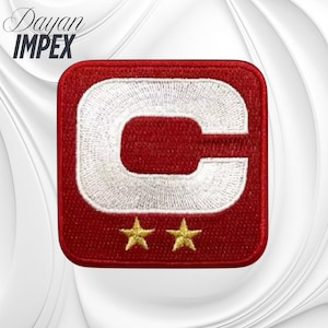 May include: Red embroidered patch with a white "C" design and two gold stars. The patch is square with rounded corners. The text "Dayan IMPEX" is in the upper left corner in a cursive font.