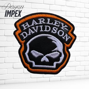May include: Embroidered patch featuring the Harley-Davidson logo with a skull design. The patch has a black background with white and orange accents. The text "HARLEY DAVIDSON" is arched across the top.
