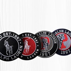 May include: Four round embroidered patches with the Ralph Lauren logo. The patches feature the Polo logo, the words "Ralph Lauren" and "Est. 1967". The patches are black, red, gray, and navy blue.