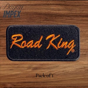 May include: A rectangular, navy blue embroidered patch with rounded corners. The patch features the words "Road King" in orange script. The patch is set against a wooden background. The text "Pack of 1" is at the bottom.