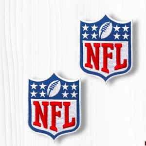 May include: Two embroidered NFL patches. Each patch features a blue shield shape with white stars and a football. The letters "NFL" are in red with a white outline. The patches are on a white background.