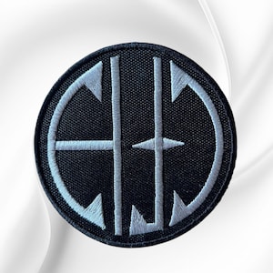 May include: A circular embroidered patch featuring a black background with a white stitched border and a central white monogram design. The design consists of two vertical lines intersected by horizontal elements forming the letters C, H, and J.