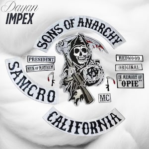 May include: A collection of embroidered patches featuring the "Sons of Anarchy" theme. The patches include the Grim Reaper with a rifle, "SAMCRO", "California", and other text-based designs. The patches are white with black and gray details.