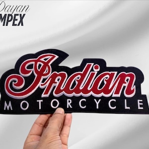 May include: Black and red embroidered patch with the words "Indian MOTORCYCLE" in a stylized font. The patch has a black border and is held by a hand against a white background. The brand name "Dayan IMPEX" is in the upper left corner.