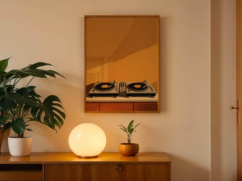 A framed mustard yellow print of turntables hangs on a wall above a wooden cabinet with a globe lamp and potted plants.
