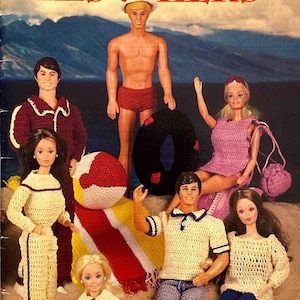 以下が含まれることがあります： ヴィンテージ「Fashion Doll HIS & HERS」の表紙。かぎ針編みの衣装を着た人形が描かれています。人形は、ピンクのドレス、白と茶色のポンチョ、白と青のセーラーシャツなど、さまざまなスタイルで着飾っています。背景にはビーチのシーンが描かれています。