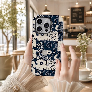 Pode incluir: Uma capa de smartphone com um padrão floral de patchwork em azul-marinho escuro e branco-creme. O design consiste em várias secções quadradas, cada uma exibindo motivos florais estilizados em esquemas de cores alternados e recorte de câmara.