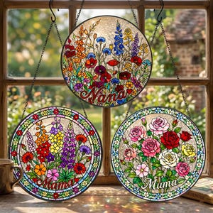 May include: Three round stained glass window hangings with floral designs. One says "Nana", another "Mama", and the third "Muma". The flowers include poppies, roses, and other colorful blooms. Each piece is framed with a decorative border and hangs from a chain.