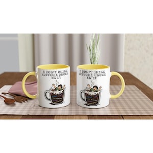 Pode incluir: Duas canecas de cerâmica branca com interior e alça amarelos. Cada caneca apresenta um gráfico de uma pessoa se afogando em uma xícara de café com o texto "I DON'T DRINK COFFEE I DROWN IN IT" e trechos de código como "if(true)", "TODO: Fix this mess" e "void loop()".