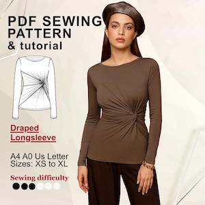 Op de afbeelding: Een vrouw draagt een bruine top met lange mouwen en draperie. De afbeelding bevat tekst: "PDF Sewing Pattern & tutorial", "Draped Longsleeve" en maat informatie. De naaivaardigheid wordt aangegeven met zwarte en witte stippen.