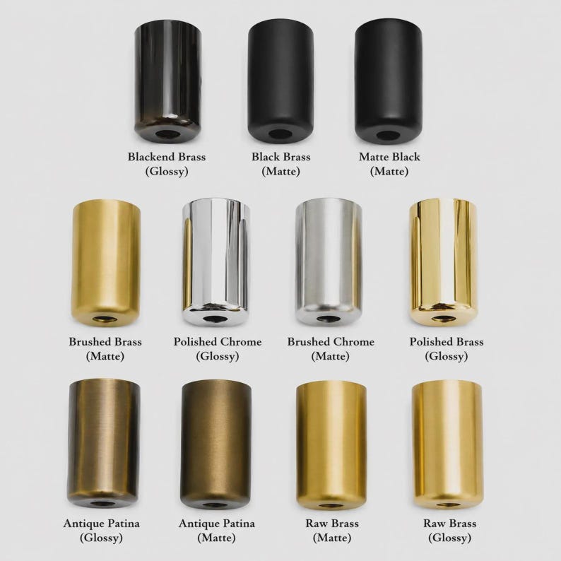 May include: A collection of twelve cylindrical metal knobs arranged in three rows. The finishes include Blackened Brass, Black Brass, Matte Black, Brushed Brass, Polished Chrome, Brushed Chrome, Polished Brass, Antique Patina, and Raw Brass.