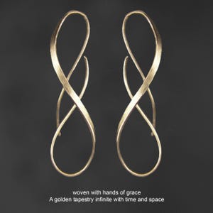 K&ouml;nnte beinhalten: Ein Paar goldfarbene Ohrringe mit einem l&auml;nglichen, gedrehten Unendlichkeits-Schleifendesign und einer strukturierten Oberfl&auml;che. Unter den Ohrringen steht der Text: woven with hands of grace, A golden tapestry infinite with time and space.