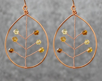 May include: A pair of copper wire earrings with a tree branch design and amber and yellow glass beads.
