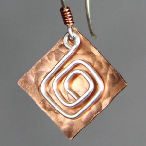 May include: Copper and silver earrings with a hammered copper square and a silver wire spiral design.