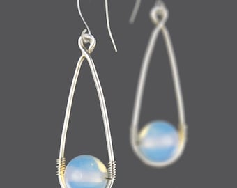 May include: Silver teardrop earrings with a light blue opal stone in each. The earrings are suspended from a silver wire loop.