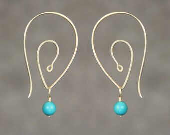 May include: A pair of gold earrings with a unique, abstract design. Each earring features a turquoise bead dangling from the bottom.