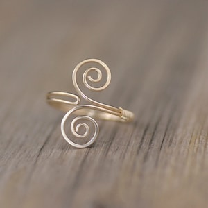 May include: A gold wire ring with a double spiral design.
