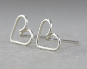 May include: A pair of silver heart-shaped stud earrings. The earrings are made of thin wire and are simple and delicate.