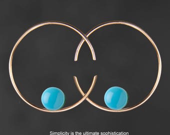 May include: A pair of gold hoop earrings with turquoise stones. The earrings are simple and elegant.