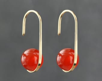 May include: A pair of gold dangle earrings with a red carnelian bead on each earring.
