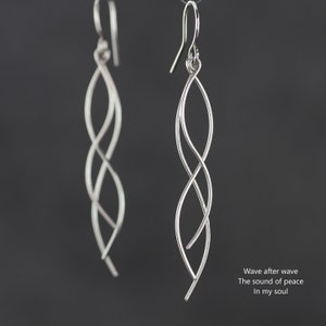 以下が含まれることがあります： ねじれた波のようなデザインのシルバー製ドロップイヤリングのペア。イヤリングは長く繊細で、どんなジュエリーコレクションにも美しいアクセントになります。  波が次々と 平和の音 私の魂の中で