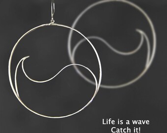 May include: Silver hoop earrings with a wave design. The earrings are large and have a minimalist style. The text "Life is a wave Catch it!" is written below the earrings.