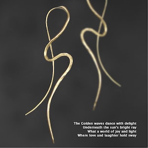 以下が含まれることがあります： 波打つような抽象的なデザインのゴールドトーンのイヤリングのペア。イヤリングは薄いハンマードメタル製で、繊細で流れるような形をしています。