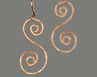 May include: A pair of copper earrings with a hammered finish. Each earring is shaped like a double spiral.