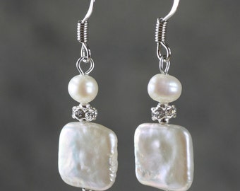 May include: A pair of silver earrings with white baroque pearl drops and clear rhinestone accents.