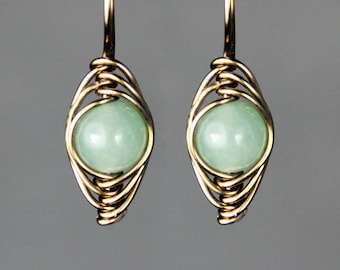 May include: A pair of gold wire wrapped earrings with light green gemstone beads.