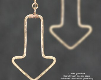 May include: Gold arrow earrings with a hammered texture. The earrings are shaped like a downward pointing arrow.