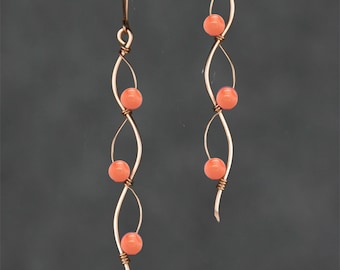 May include: A pair of long, delicate earrings with a twisted wire design and coral-colored beads.
