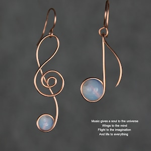 May include: A pair of earrings featuring a treble clef design with a light blue gemstone. The earrings are made of rose gold wire.