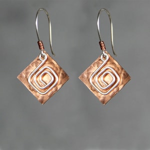 May include: A pair of copper earrings with a hammered finish and a silver wire spiral design.