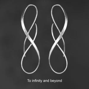 K&ouml;nnte beinhalten: Ein Paar silberfarbene Ohrringe mit einem l&auml;nglichen, gedrehten Unendlichkeits-Schleifendesign und einer geb&uuml;rsteten Metalloberfl&auml;che. Der Text "To infinity and beyond" ist in Wei&szlig; am unteren Bildrand unter den Ohrringen zentriert.