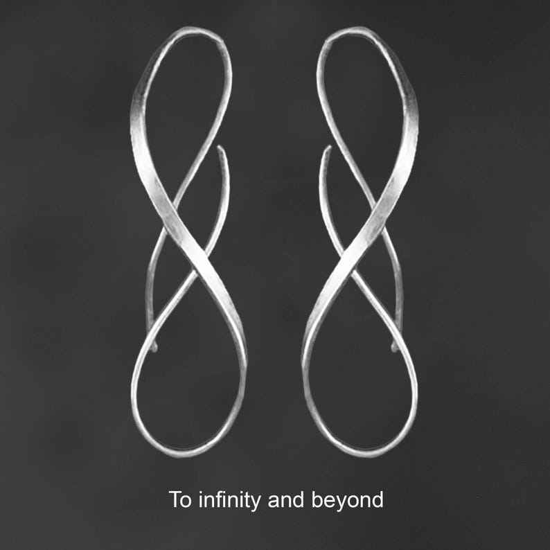 K&ouml;nnte beinhalten: Ein Paar silberfarbene Ohrringe mit einem l&auml;nglichen, gedrehten Unendlichkeits-Schleifendesign und einer geb&uuml;rsteten Metalloberfl&auml;che. Der Text "To infinity and beyond" ist in Wei&szlig; am unteren Bildrand unter den Ohrringen zentriert.