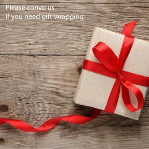 May include: A white gift box with a red ribbon tied in a bow. The box is sitting on a wooden surface. The text "Please convo us if you need gift wrapping" is visible at the top of the image.