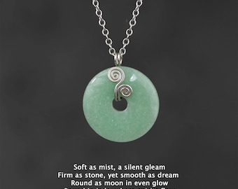 May include: A silver chain necklace with a round green jade pendant. The pendant has a silver wire design in the shape of two swirls.