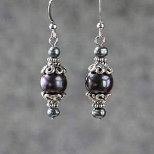 May include: A pair of silver earrings with dark gray pearl beads and silver filigree accents.