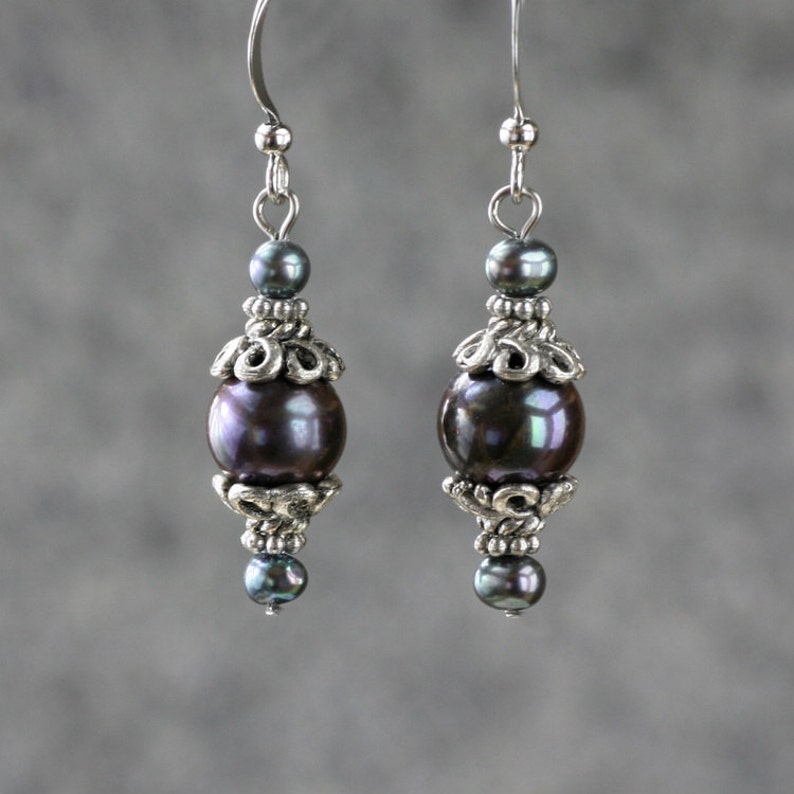 May include: A pair of silver earrings with dark gray pearl beads and silver filigree accents.