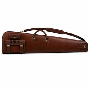 May include: A dark brown leather gun case featuring a long, tapered shape with a top handle and an adjustable shoulder strap. The exterior includes a small flap pocket and a larger buckled storage compartment with brass hardware and metal rivets.