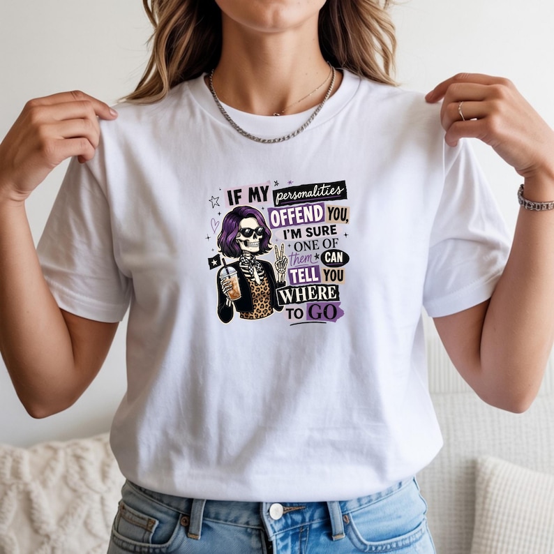 May include: A white t-shirt featuring a graphic of a skeleton with purple hair, sunglasses, and a leopard print top, holding a drink and making a peace sign. The text reads: IF MY personalities OFFEND YOU, I'M SURE ONE OF them CAN TELL YOU WHERE TO GO.