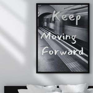 Peut inclure: Impression en noir et blanc encadrée, représentant une scène de métro avec un train flou. Le texte "Keep Moving Forward" est écrit en blanc sur l'image, dans un style manuscrit.