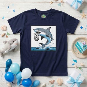 May include: A navy blue short-sleeve t-shirt featuring a graphic print of a shark jumping out of water. The graphic includes the name Wade and the number 6 in a metallic silver font. The shirt has a round neckline and a standard fit.